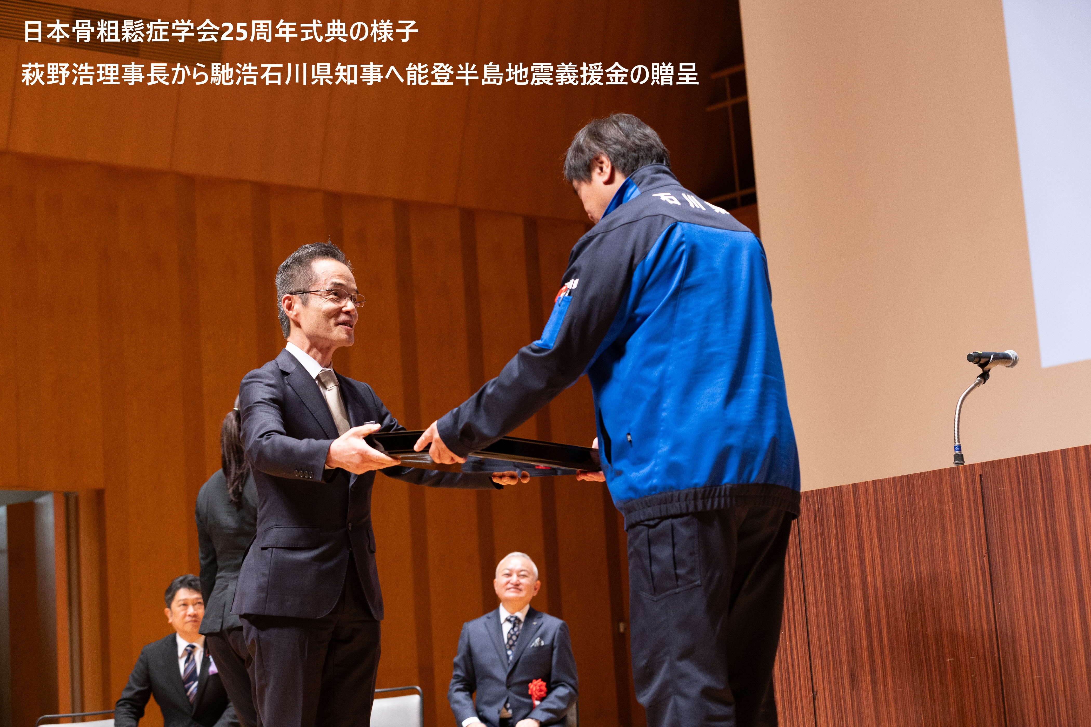 日本骨粗鬆症学会25周年式典の様子、萩野浩理事長から馳浩石川県知事へ能登半島地震義援金の贈呈